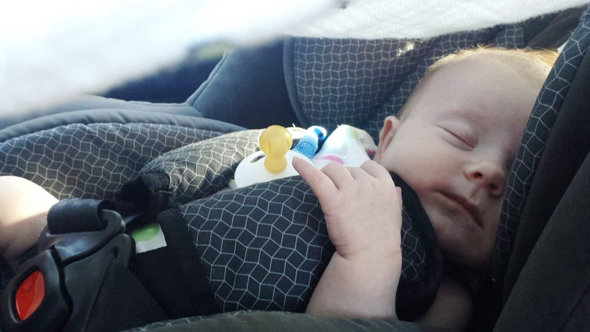 bébé qui dort dans un siege bébé